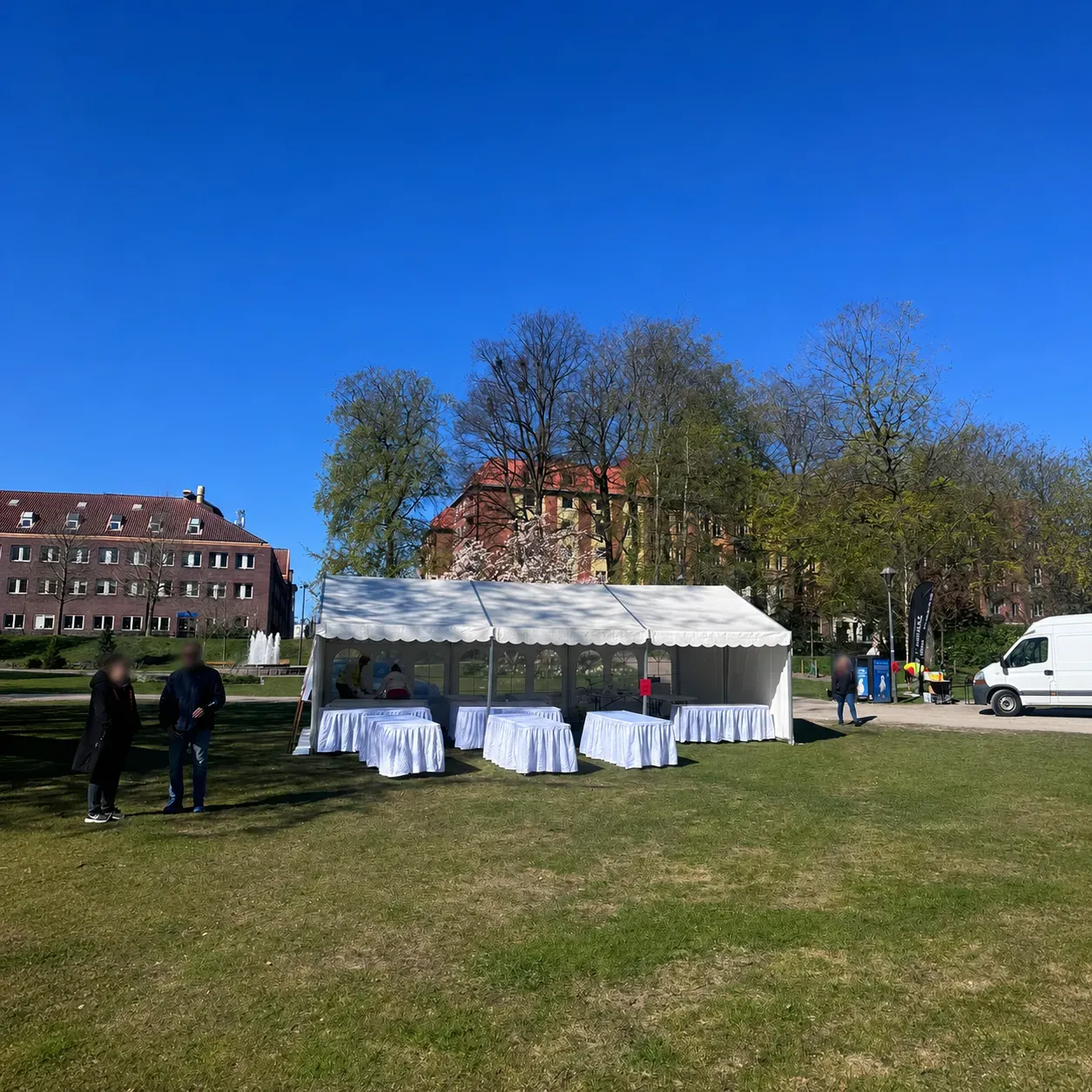 Helvitt partytält 6x9 med bord uppställt i parkmiljö under blå himmel.